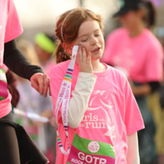 One Girls on the Run participant holds a 5K medal to her face
